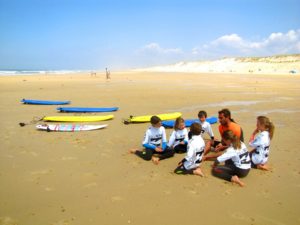 groupe d'enfants sur la plage qui se préparent à aller surfer
