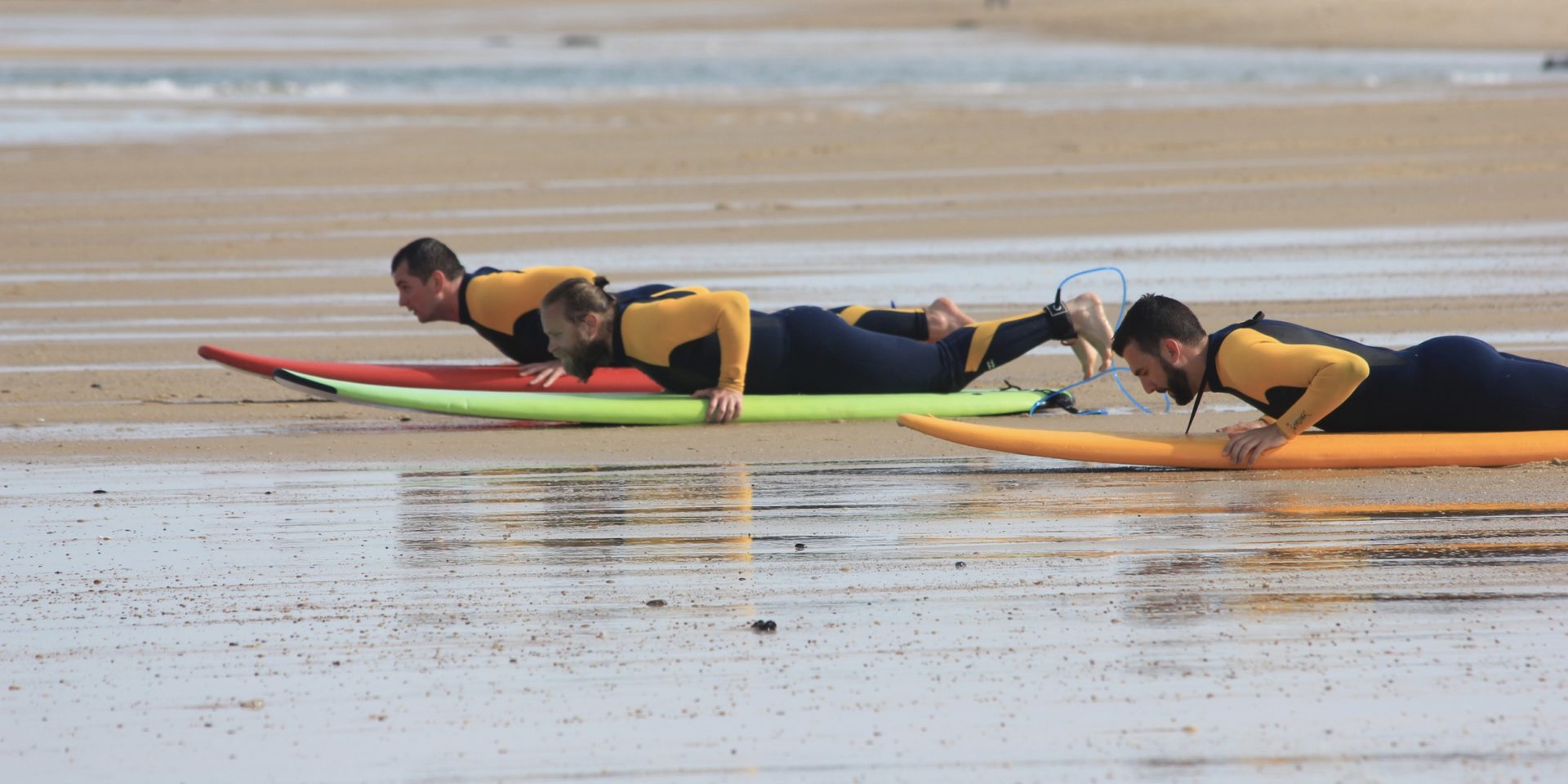 trois personnes allongées sur des planches de surf à Lacanau