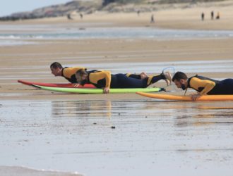 trois personnes allongées sur des planches de surf à Lacanau
