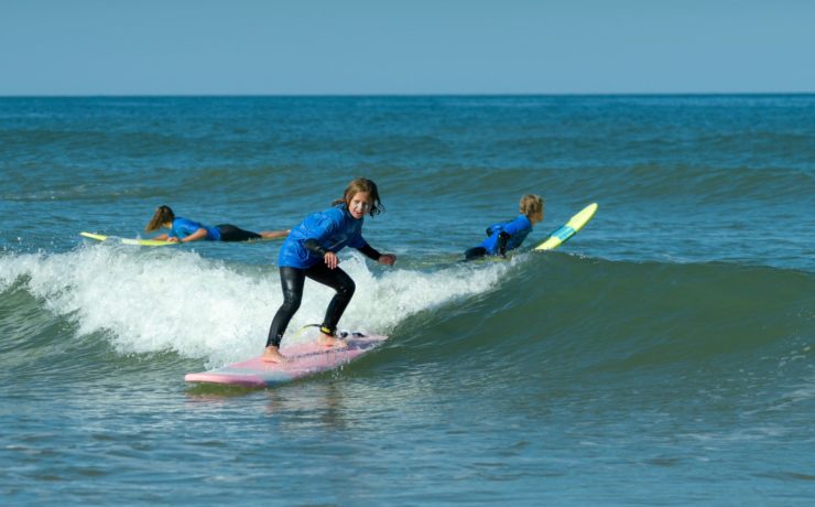 une petite fille qui surfe sur une vague à lacanau ocean avec une planche rose chez Magic Surf School