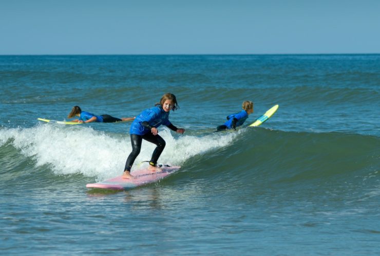 une petite fille qui surfe sur une vague à lacanau ocean avec une planche rose chez Magic Surf School