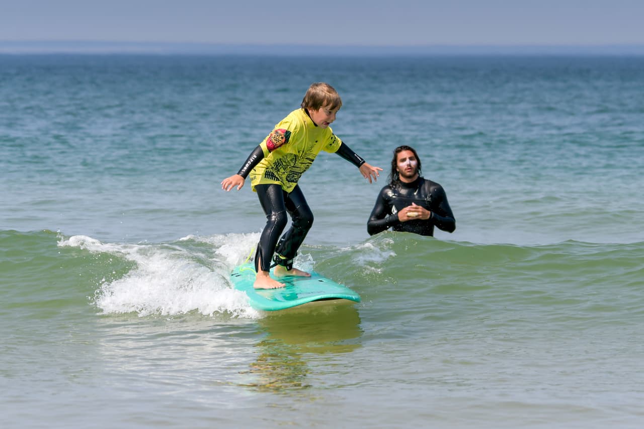 stage-enfant-2 Une jeune garçon de 5-6 ans debout sur sa planche de surf avec Magic Surfschool à Lacanau